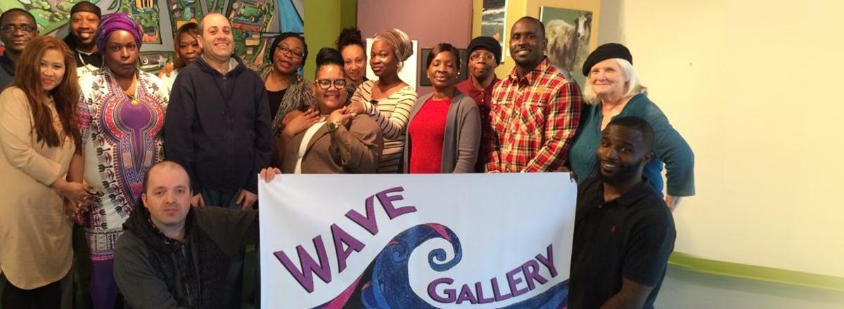 Wave art gallery, crowd of artists holding a sign in front of them