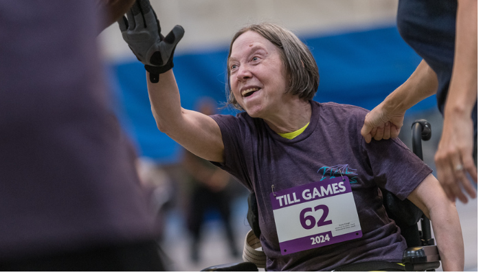 Woman in wheelchair high fiving at track event