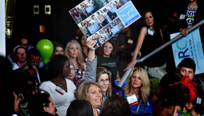 A group in the crowd with Sandy holding up a sign