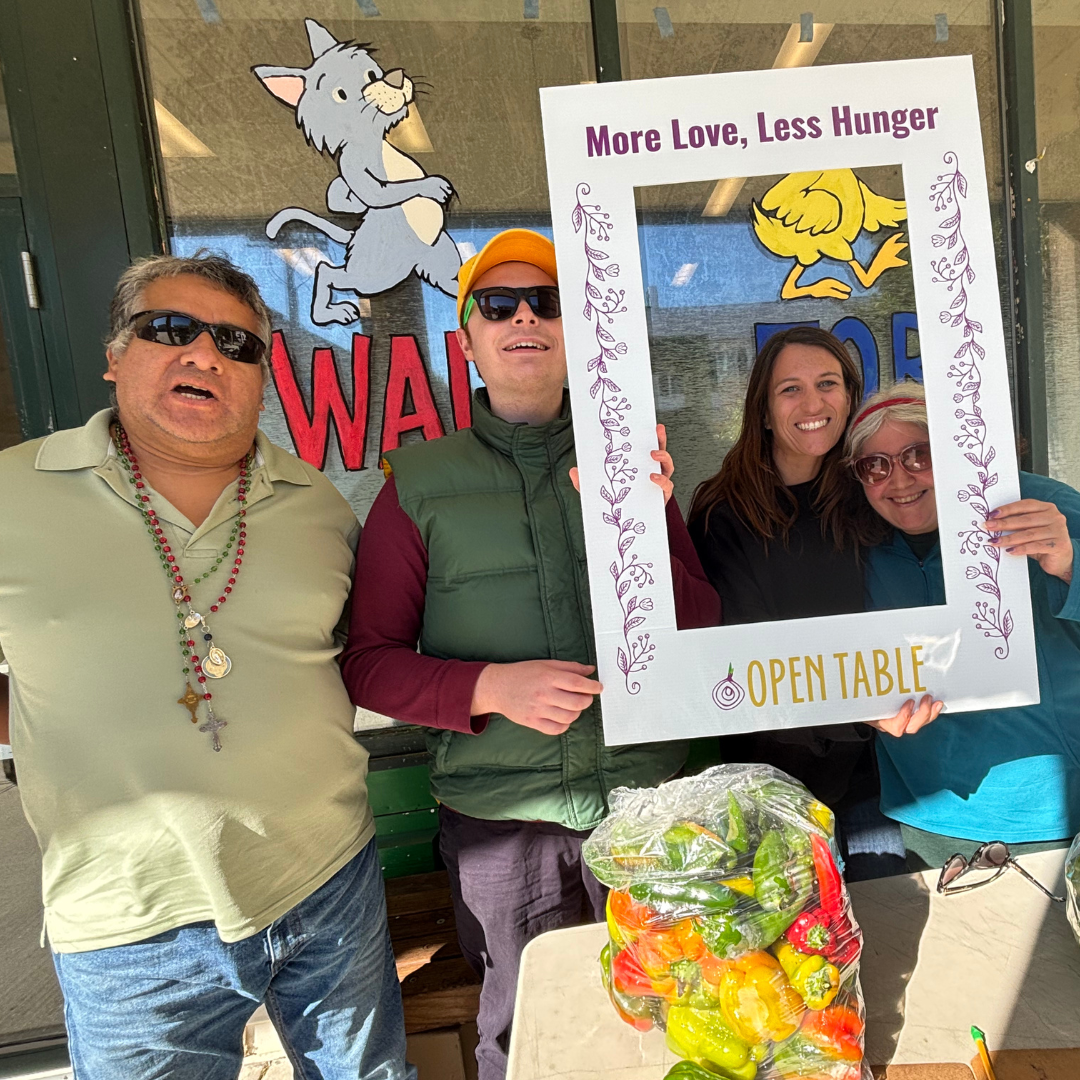 Three people holding up a sign that says "More Love, Less Hunger"
