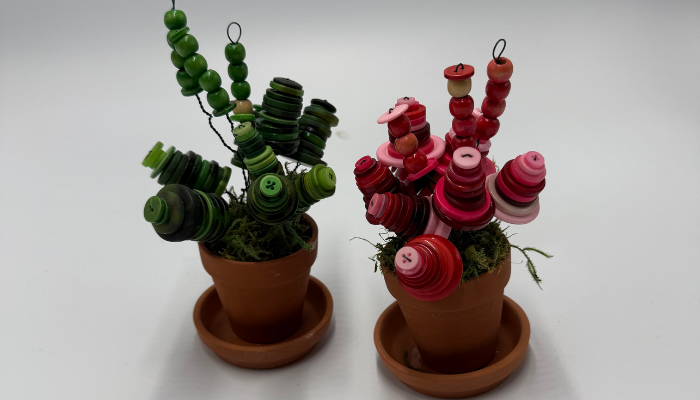 Two mini pots with green and red buttons as plants