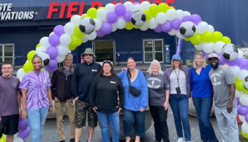 Group of adults standing under balloon arch