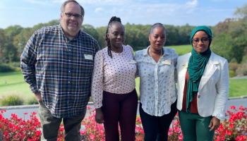 Photo of 4 people smiling together on a sunny day at luncheon