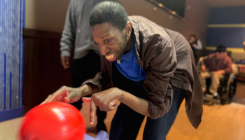 Individual rolling a red bowling ball 