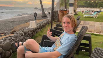 A man holding up a peace sign in front of the beach in Costa Rica