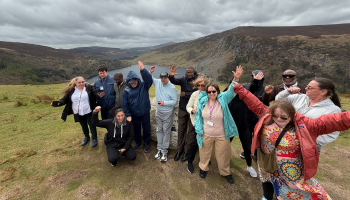 Group photo on a big hill with nice view in the back in Ireland