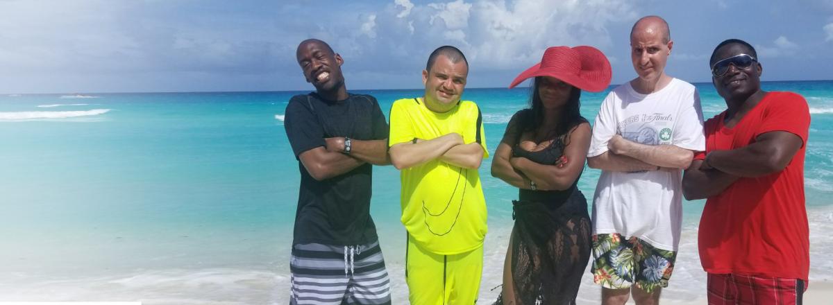 Cancun, five adults standing in a row with their arms crossed and blue water behind them