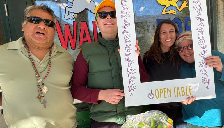Three people holding up a sign that says "More Love, Less Hunger"